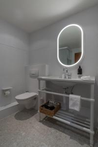 a bathroom with a sink and a toilet and a mirror at Boutique Hotel Engadinerhof - A Home for Generations in Pontresina