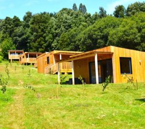 a row of wooden houses in a field with trees at Cabañas Compostela - Cabaña Sarela in Santiago de Compostela