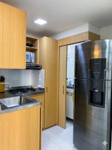 a kitchen with a stainless steel refrigerator and wooden cabinets at Cartagena Flat Resort in Cartagena de Indias