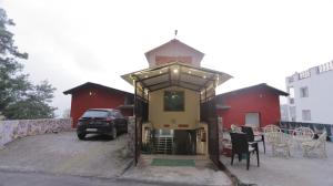 a small red building with a car parked in front of it at The himaliyan munros in Rānīkhet