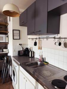a kitchen with black cabinets and a sink at Spacious Studio Paris La villette-Metro in Paris