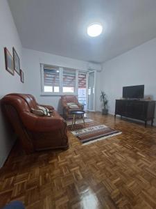 a living room with a leather couch and a television at Apartmani E&A Jasmina Okanović in Gradačac