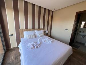 a bed with white sheets and pillows on it at Appartement 3 vue sur mer in Tamraght Ou Fella