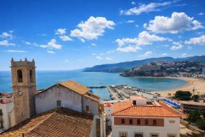 a view of a city with a clock tower and a beach at Portal Fosc Suites in Peniscola
