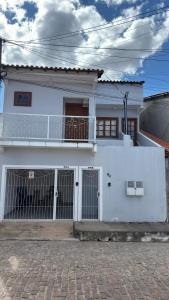 a white house with a fence in front of it at Escalada Hospedagem Térreo in Mucugê