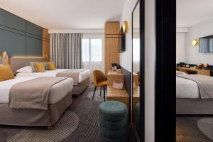 ein Hotelzimmer mit zwei Betten und einem Schreibtisch in der Unterkunft Hôtel Roissy in Lourdes