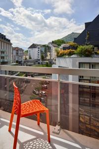 ein orangefarbener Stuhl steht auf einem Balkon in der Unterkunft Hôtel Roissy in Lourdes