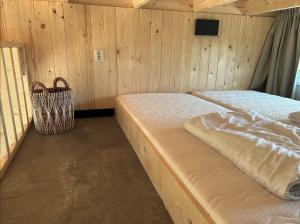 two beds in a room with wooden walls at Tiny House in Kesteren