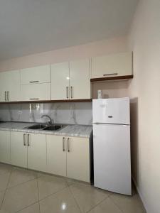 a kitchen with white cabinets and a white refrigerator at eljos house permet in Përmet +43 photos