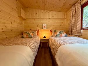 two beds in a log cabin with a lamp between them at Lake District Woodland Cabin - Close to Ambleside & Langdale Valley in Ambleside +14 photos
