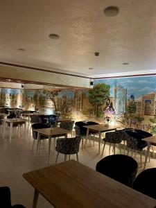 a restaurant with tables and chairs and a mural on the wall at Hotel Al Amir palace boutique in Bukhara
