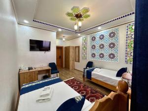 a hotel room with two beds and a tv at Hotel Al Amir palace boutique in Bukhara