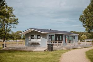 ein kleines graues Haus mit Veranda und Zaun in der Unterkunft Safaritent Mini Lodge in Kesteren