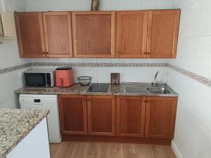 a kitchen with wooden cabinets and a sink and a microwave at Résidence soleilla in Le Barcarès +4 photos