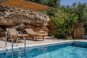 a pool with two chairs next to a stone wall at Villa Aethra in Riglia