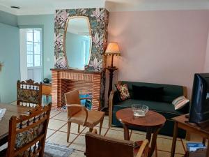 a living room with a green couch and a mirror at La Georginette in Saint-Georges-sur-Cher