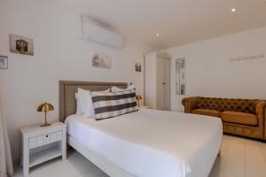 a bedroom with a large white bed and a couch at Hôtel Le Square in Saint-Pierre-dʼOléron
