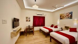 a hotel room with two beds and a television at Ayaf Homes in Pondicherry