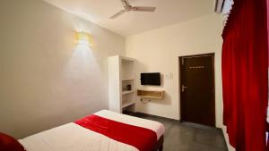 a bedroom with a bed and a tv and a red curtain at Ayaf Homes in Pondicherry