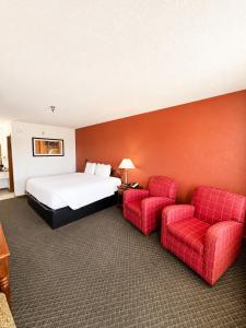 a hotel room with a bed and two red chairs at Carriage House Inn in Branson +34 photos