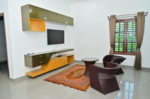 a living room with a tv and some chairs at Relaxing Villa in Mysuru! in Mysore