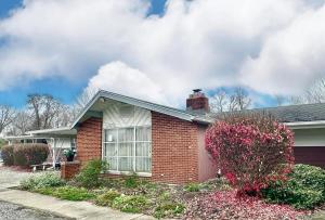 a brick house with a flowering bush in front of it at Flora Motel in Flora