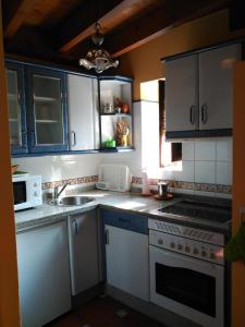 a kitchen with white cabinets and a sink and a microwave at Casa Rural Casa Azul in Villahormes