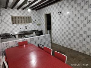 a red table and chairs in a room with a kitchen at Chácara Volito in Cotia