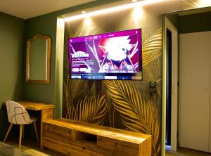 a flat screen tv on a wall in a room at La chambre du moulin dort in Chénelette