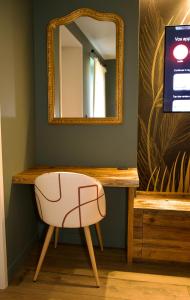 a mirror on a desk with a chair in a room at La chambre du moulin dort in Chénelette