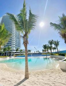 a palm tree on the beach in front of a building at Sky26 Stays by Paula & Hudson in Pampang