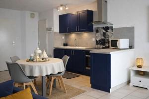 a kitchen with blue cabinets and a table with a microwave at Centre ville de Sarzeau, appartement au calme avec jardinet et parking privé in Sarzeau