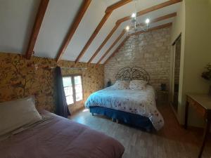 a bedroom with two beds and a stone wall at LE SOURCIER in Argançon