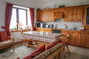 a kitchen with wooden cabinets and a table in it at Scoor - Garden Cottage in Bunessan +6 photos