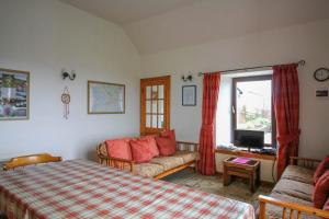 a bedroom with a bed and a couch and a window at Scoor - Garden Cottage in Bunessan