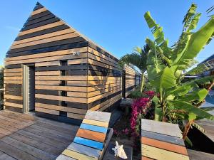 a wooden building with two benches on a deck at La Case des Caraïbes in Le Gosier