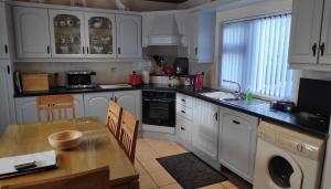 a kitchen with white cabinets and a table and a sink at Katie's Cottage in Laghy