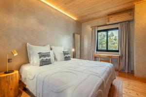 a bedroom with a large white bed with a window at Casa do Incenso in São Roque do Pico
