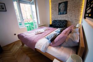 a bedroom with a large bed with pink sheets and pillows at The Bohemian Residence in Belgrade
