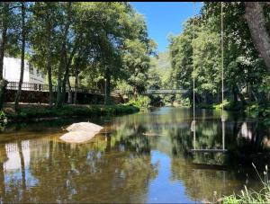 an umbrella in a river with trees and a bridge at Casa do Rio Alva in Caldas de São Paulo