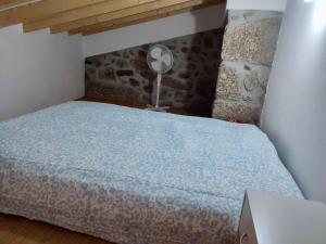 a bedroom with a bed with a blue bedspread and a fan at Casa do Rio Alva in Caldas de São Paulo