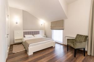 a white bedroom with a bed and a chair at Galaktyka Hotel in Stantsiya Biskovitse
