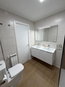 a white bathroom with a toilet and a sink at Entre Plazas in Cáceres +11 photos