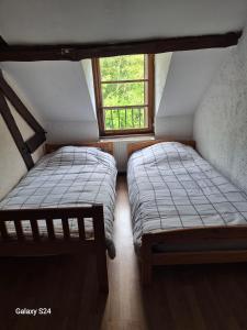 two beds in a small room with a window at Ancienne étable in Pierrefitte-sur-Sauldre