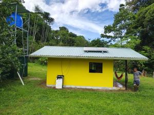 a boy standing in front of a yellow house at Finca Paz y Flora in Drake