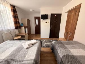 a bedroom with two beds and a table and a television at U Marzeny in Malbork