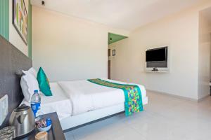 a white bedroom with a bed and a tv at Treebo Kuber Palace with Swimming Pool in Mahabaleshwar