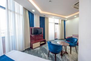 a hotel room with a television and blue chairs at Denis Hotel Tbilisi in Tbilisi City