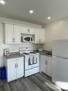 a kitchen with white cabinets and a white stove top oven at Riverfront Studios Inn in Sault Ste. Marie
