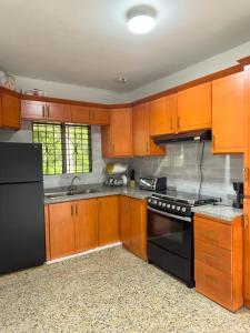 a kitchen with wooden cabinets and black appliances at Brisa del Rio Jimenoa in Jarabacoa